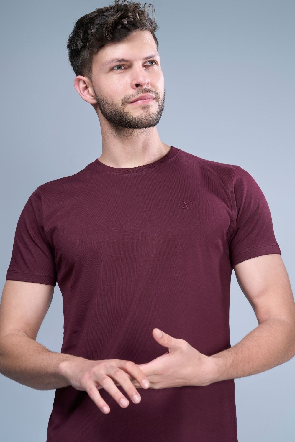 A model wearing Heng Maroon colored, Solid T shirt for men, with half sleeves and round neck.