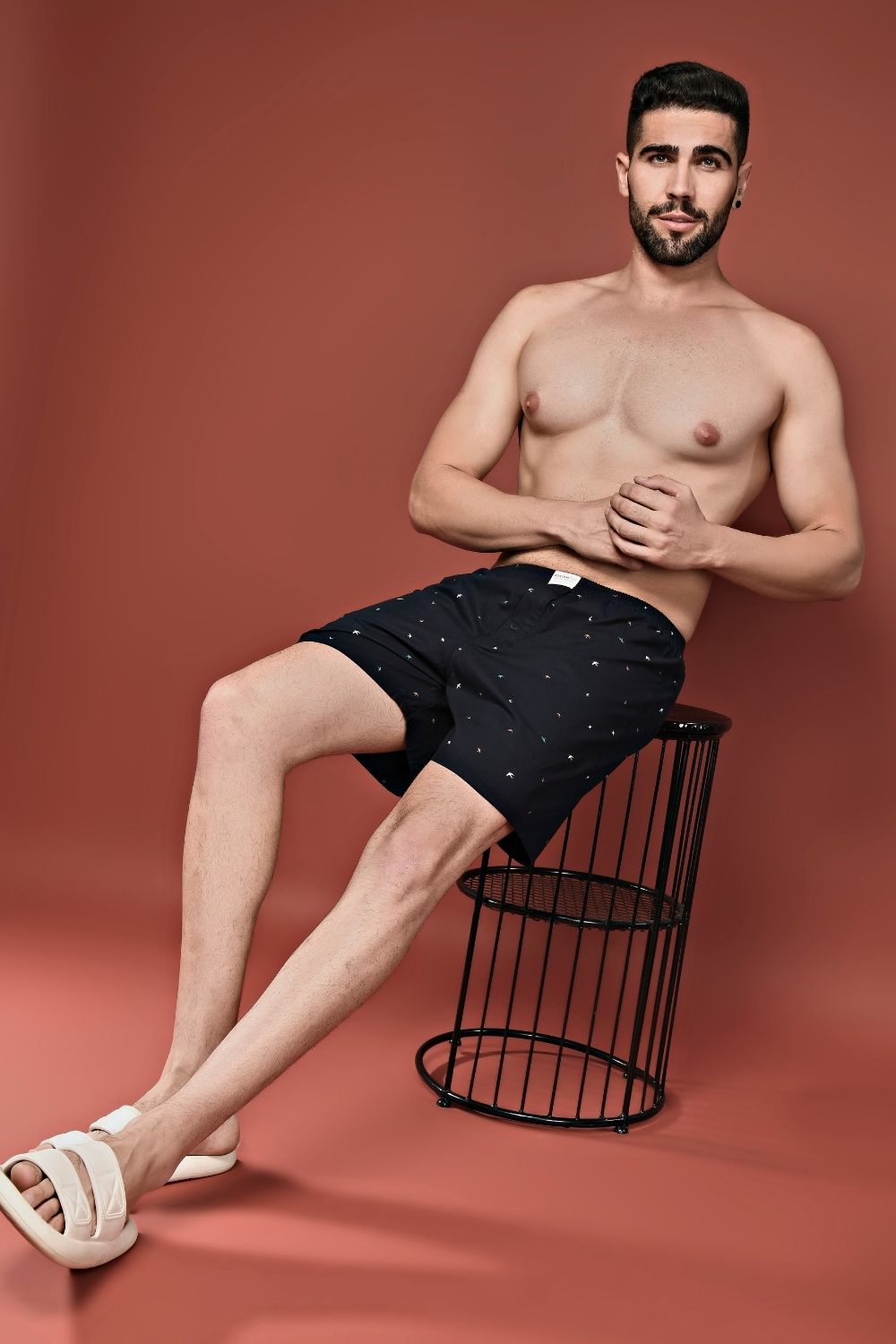 A model wearing Teal Navy colored all over printed cotton boxer for men with back pockets.