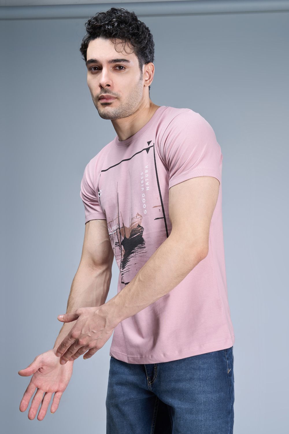 A model wearing Rose pink colored, cotton Graphic T shirt for men, half sleeves and round neck.