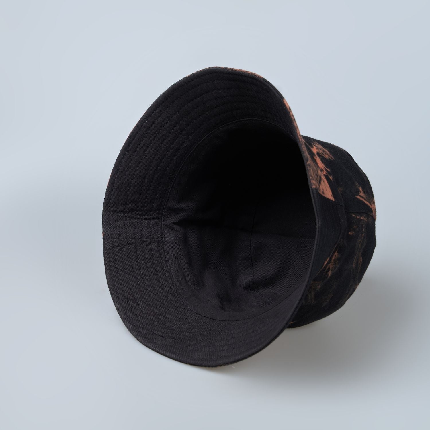 Black and orange colored, lightweight bucket hat for men, close up.