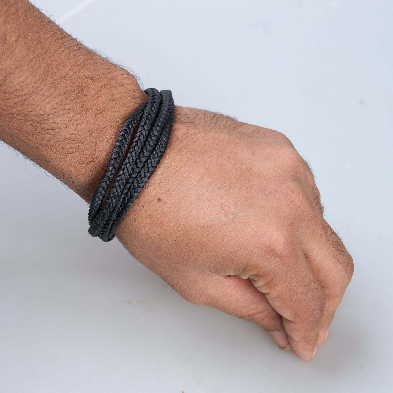 Display of a Black colored Multi-string Bracelet for men, with screw clasp on a hand.
