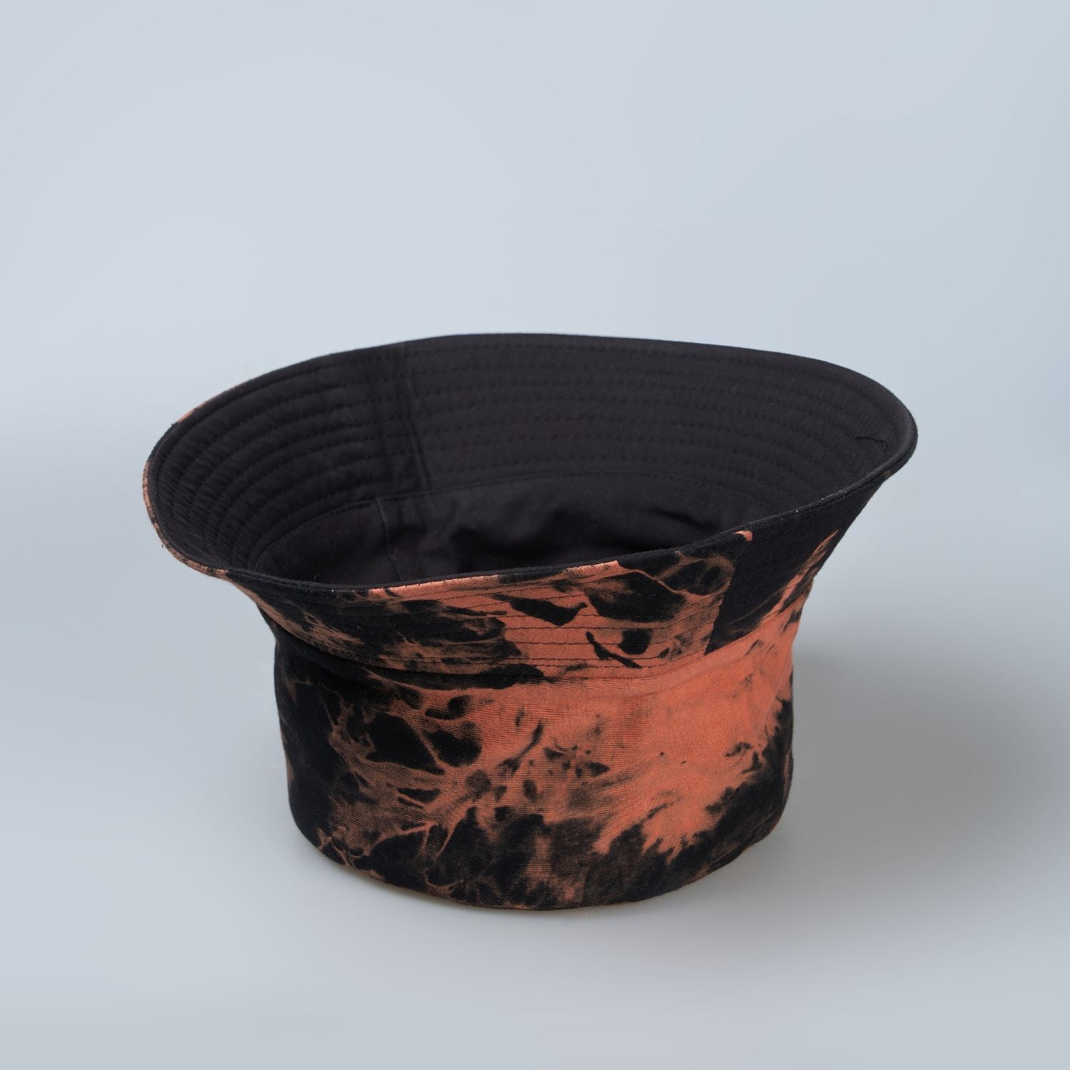 Black and orange colored, lightweight bucket hat for men, upside down.