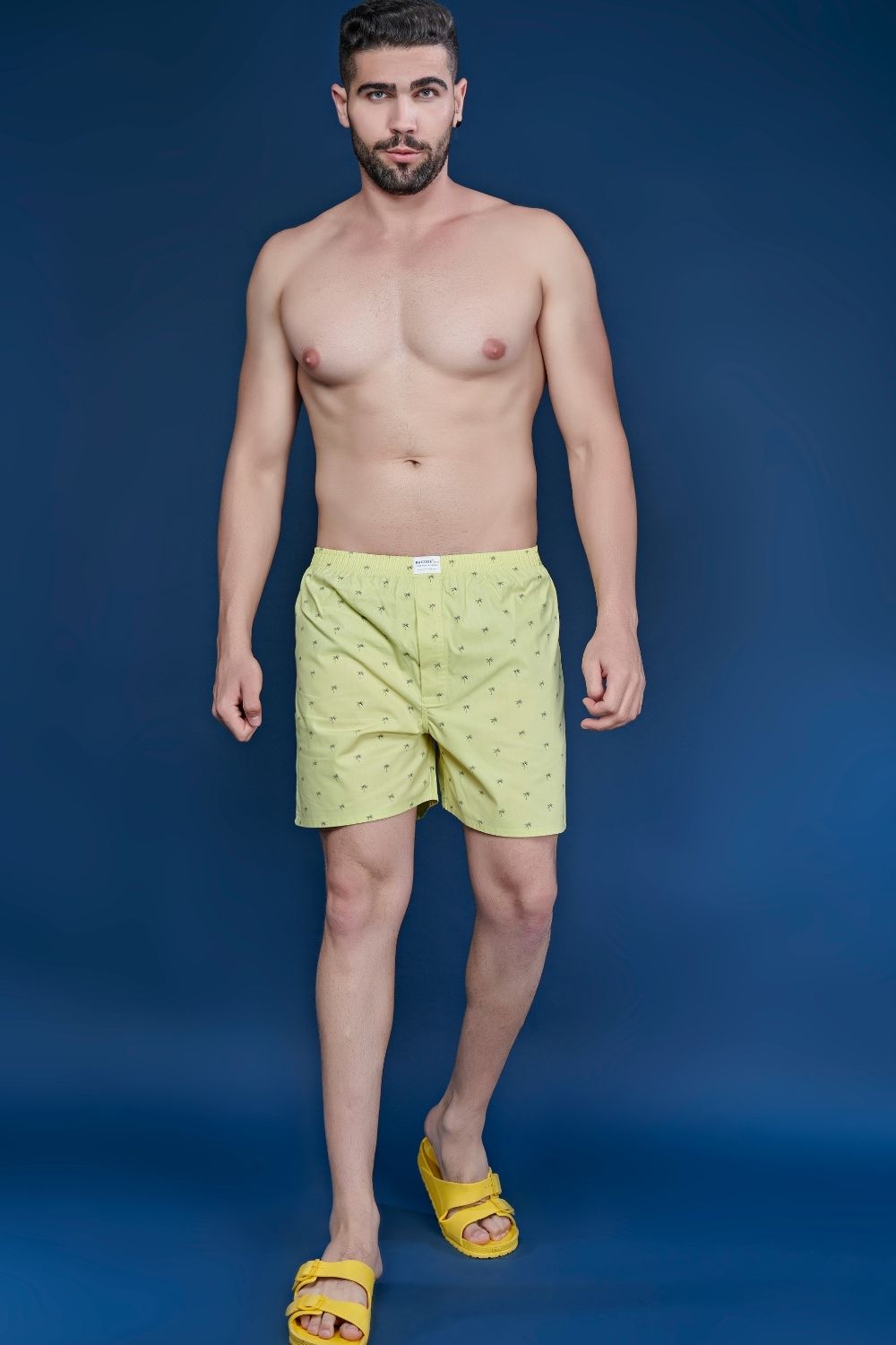 A model wearing Lemon yellow colored all over printed cotton boxer for men with back pockets.