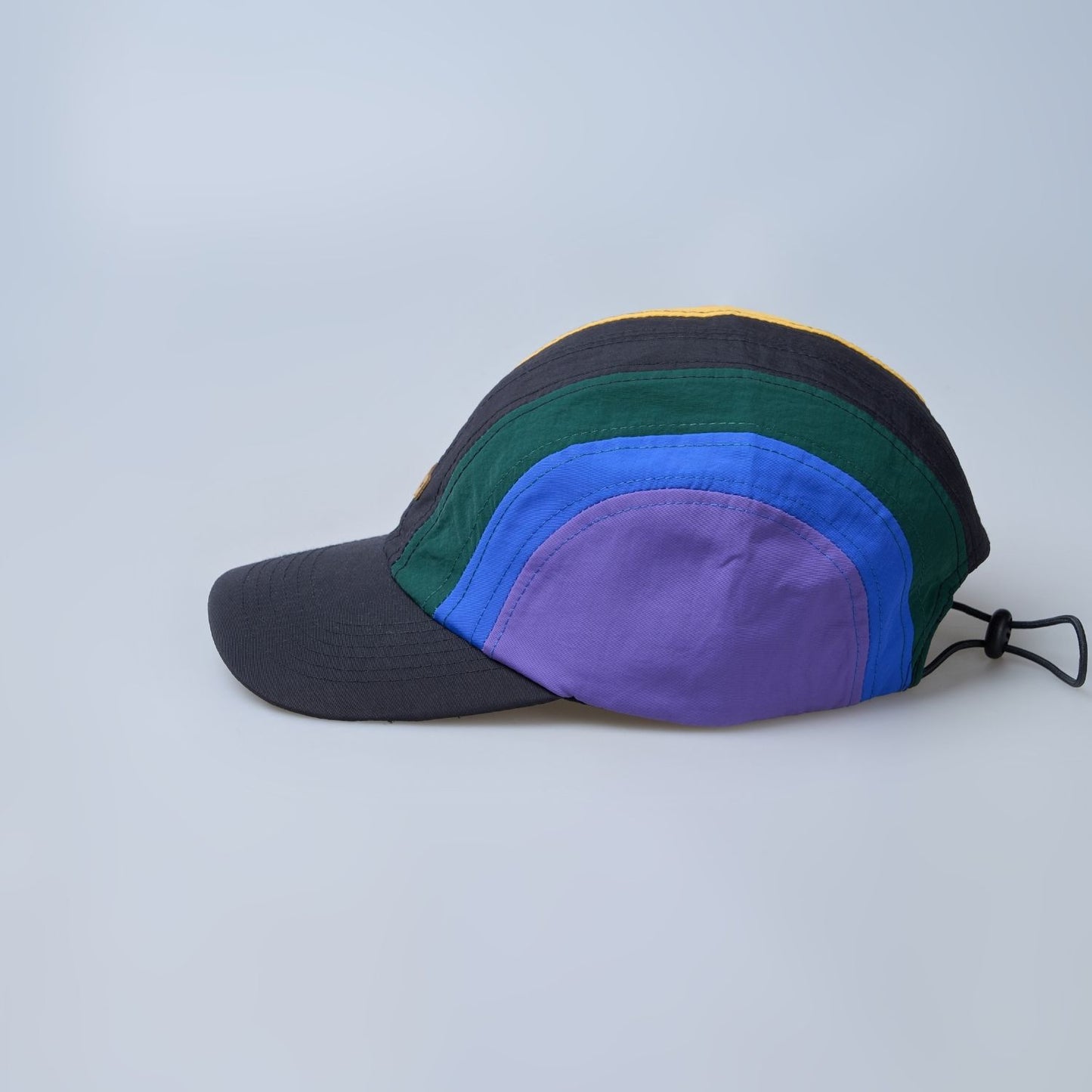 Multi colored, wide brim cap for men with adjustable strap, side view.