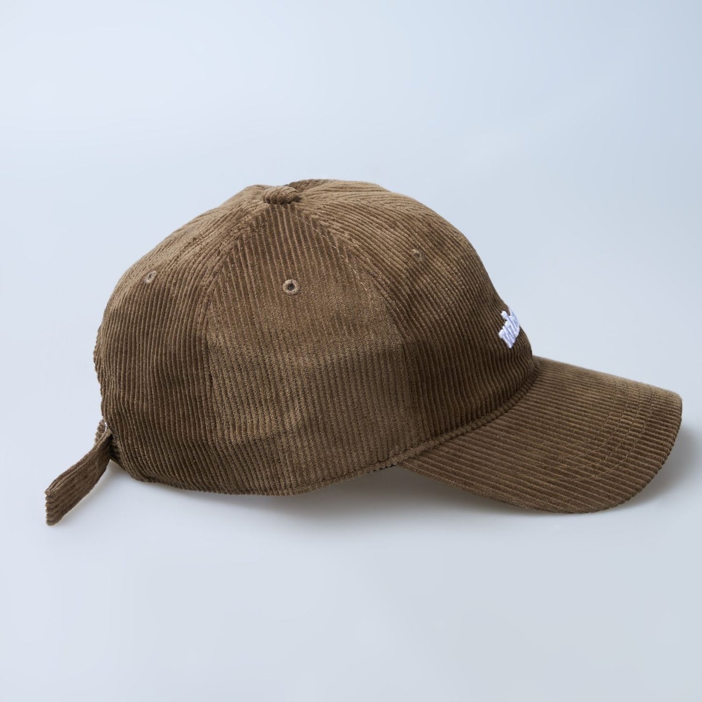 Brown colored cap for men with 'what' text written on it, side view.
