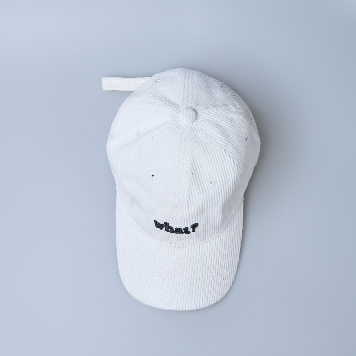 White colored cap for men with 'what' text written on it, up view.
