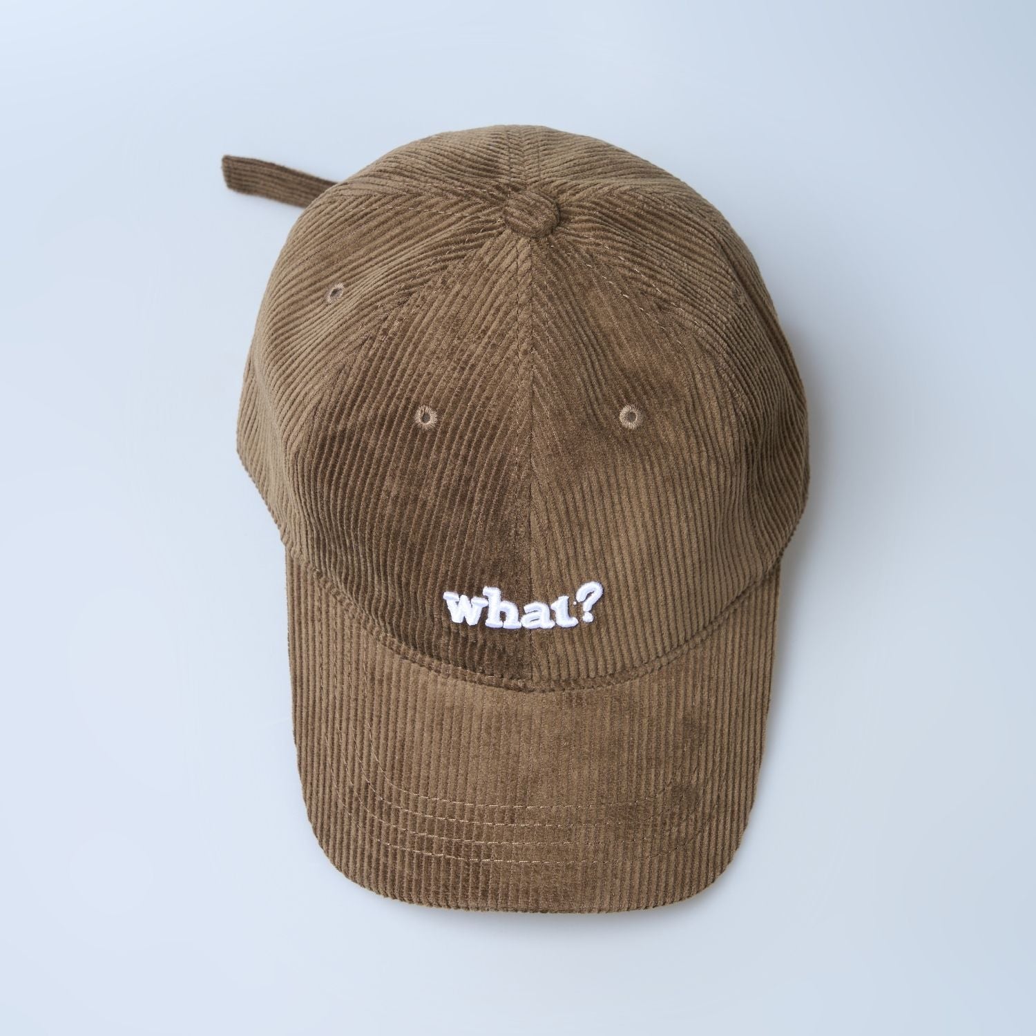 Brown colored cap for men with 'what' text written on it, top view.