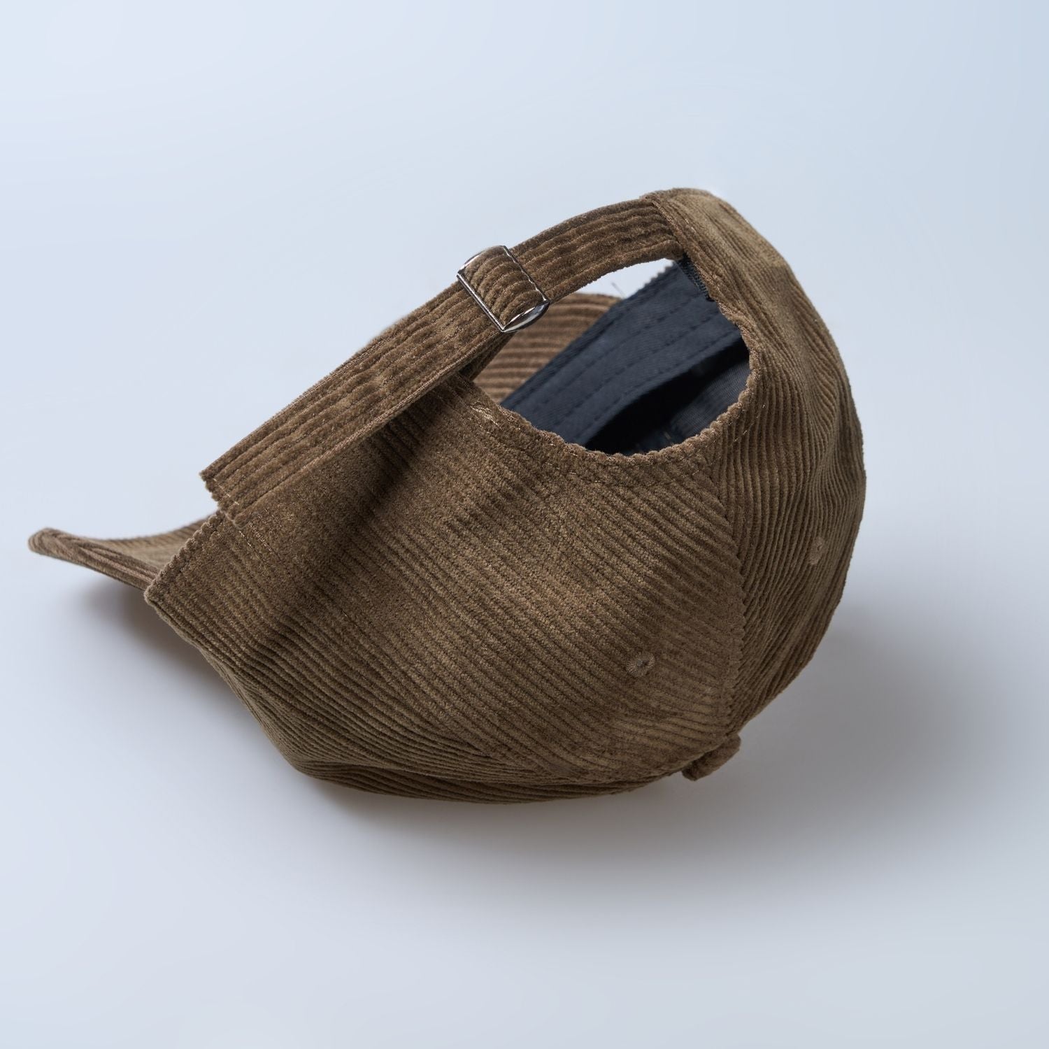 Brown colored cap for men with 'what' text written on it, adjustable strap closeup.