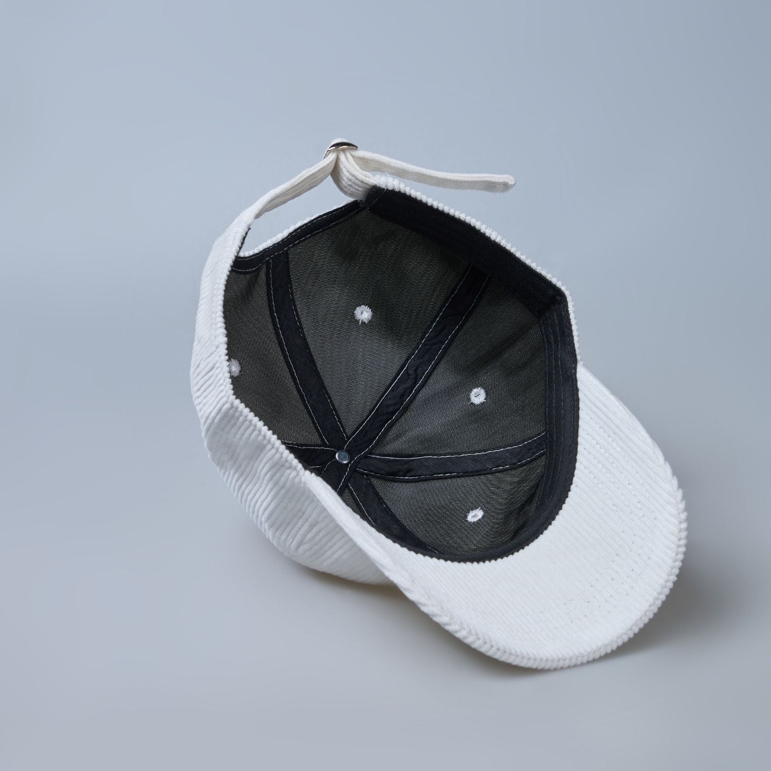 White colored cap for men with 'what' text written on it, inside view.